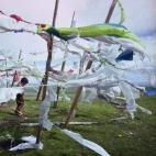 Un joven tibetano juega junto a banderas de plegarias que ondean al viento. Estas banderas tradicionalmente son impresas utilizando tipos de madera que poseen textos e imágenes.