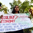 Una joven sostiene una pancarta mientras participa en una protesta contra la inacci&oacute;n gubernamental hacia el colapso clim&aacute;tico y la contaminaci&oacute;n ambiental en la India.