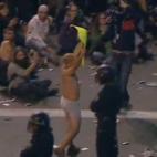 Un manifestante en ropa interior muestra una pancarta frente a la policía