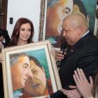 En esta foto del 1 de diciembre de 2011, la presidenta argentina Cristina Fernández sonríe al recibir de manos de su colega venezolano Hugo Chávez una pintura de su fallecido marido Néstor Kirchner y del propio Chávez, en Caracas. La incert...