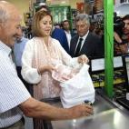 María Dolores de Cospedal, ayuda a un hombre a guardar su compra durante su visita a la sede de la Asociación de Pequeños Agricultores de Guadalajara.