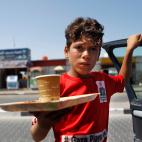 Yunis, de 13 a&ntilde;os, sostiene una bandeja en la que porta una taza de caf&eacute; en Gaza. Yunis es el mayor de 12 hermanos y su padre lleva dos a&ntilde;os sin empleo, as&iacute; que &eacute;l ha tenido que dejar de estudiar para intentar ...