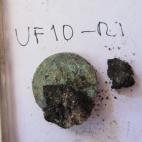 Una moneda, unida a un resto de textil.