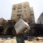 Un ciudadano saca material informático tras el asalto de la sede.