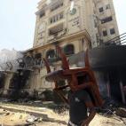 Otro manifestante saca un silla de la sede quemada.