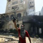 Un manifestante sostiene una pistola presuntamente utilizada por miembros de los Hermanos Musulmanes e incautada en el asalto a la sede.