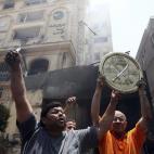 Un manifestante sostiene una placa distintiva de la Sociedad de los Hermanos Musulmanes tras el asalto a su sede principal.
