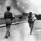 Una refugiada corre hacia la frontera de Francia con un ni&ntilde;o en brazos.