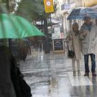 Varias personas se protegen de la lluvia que esta cayendo en Gandía.