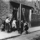 Alrededor de 1892: Niños de los suburbios improvisan un columpio con una farola y cuerda (Foto de Paul Martin/Getty Images)