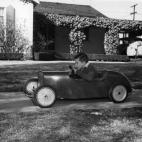 Un niño en su coche a pedales en el jardín de su casa. (Foto del National Motor Museum/Heritage Images/Getty Images)