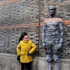 Una niña posa junto a un hombre camuflado en una parede en Shanghái, China.