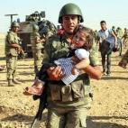 Un soldado turco lleva en brazos a una niña siria en la frontera de Akcakale.