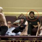 Ella se quita la camiseta mientras su compañera se encarama a la columna. Pero él, sigue mirando al frente. Al fin y al cabo a lo que ha venido al Congreso es a seguir el debate.
