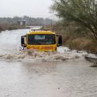 Una grúa pasa por la rambla de la Cañada Morcillo, en el polígono industrial de La Estrella en Molina de Segura, este jueves durante un momento de intesa lluvia.