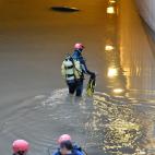 Miembros de los GEAS y bomberos trabajan en la zona donde aún permanece un vehículo que ha quedado atrapado en el paso subterráneo y en el que ha fallecido una persona.