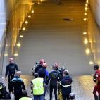 Miembros de los GEAS y bomberos trabajan en la zona donde aún permanece un vehículo que ha quedado atrapado en el paso subterráneo y en el que ha fallecido una persona.