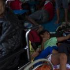 Un anciano, junto a sus nietos, en una de las tiendas de campaña que el Gobierno de Filipinas ha habilitado para algunos de los evacuados en el aeropuerto de Taclobán, el 13 de noviembre de 2013.