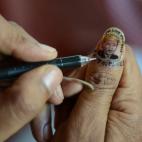Una artista india pinta una miniatura de Mandela en una de sus uñas