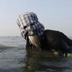 El pescador Ompong Vargas, que se protege del sol con un pasamontañas de tela, sostiene un pez en la boca mientras usa las manos para manejar la red. Laguna de Bay en Taguig City, Manila, Filipinas, el 24 de mayo.