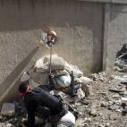 Un combatiente del Ejército Libre de Siria sostiene la cabeza de un maniquí para atraer y localizar francotiradores durante los combates en los alrededores de Damasco (Siria).