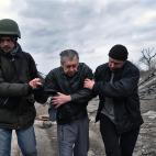 Dos voluntarios ayudan a un hombre discapacitado a cruzar un puente destrozado por los ataques.