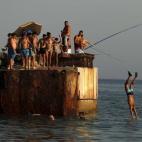 Un chico se tira desde el espigón de la playa Sacaba, en Málaga.