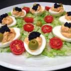 Las aceitunas son rellenas de anchoa y se decoran con sucedáneo de caviar y tomates cherry. La salsa lleva tabasco. Para prepararlos sigue la receta de Cookpad.