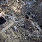Un palestino recoge un mueble de entre los escombros de una casa destruida por Israel en Beit Hanu, al norte de la Franja de Gaza.