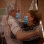 Isabel, de 96 a&ntilde;os, recibe un abrazo a trav&eacute;s de una cortina de pl&aacute;stico de su yerno, Jos&eacute; Mar&iacute;a, de 69, en un centro de mayores, en Barcelona