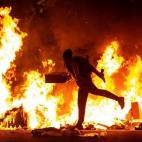 Un manifestante echa al fuego un cartón junto a la Delegación del Gobierno en Barcelona durante los incidentes producidos al finalizar la movilización convocada por los CDR, hoy martes en la segunda jornada de protestas contra la sentencia co...