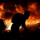 La silueta de un manifestante, frente al fuego