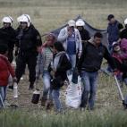 Una familia de refugiados recoge sus pertenencias e inicia un nuevo traslado bajo la vigilancia de los antidisturbios. Según señaló este lunes el portavoz del Gobierno para asuntos de refugiados, Yorgos Kyritsis, se espera que el traslado a c...
