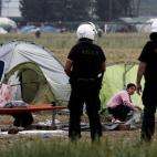 Un niño recoge sus pertenencias ante la atenta mirada de policías con cascos, aunque el gobierno heleno no quería llevar a cabo un desalojo forzoso.