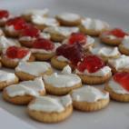 El blanco lo aporta el queso de untar y el rojo es por la mermelada de fresa. También se puede hacer con mermelada de tomate. En Cookpad puedes ver la receta.
