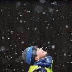 Un niño sonríe mientras mira hacia el cielo durante una nevada en Kleinmachnow, en el estado de Brandemburgo (Alemania).