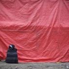 Este hombre, envuelto en una manta, descansa al lado del refugio temporal para personas sin hogar una fría mañana en Nueva Delhi (India).