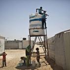 Syrian refugee children, climb a water tower to collect some, at Zaatari refugee camp, near the Syrian border, in Mafraq, Jordan, Wednesday, July 30, 2014. More than 2.8 million Syrian children inside and outside the country â nearly half t...
