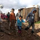 In this picture taken on Wednesday, March 12, 2014, Syrian refugee children walk between their tents on their way to a makeshift school at their refugee encampment in the Lebanese-Syrian border town of Majdal Anjar, eastern Bekaa valley, Lebanon...
