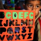 In this picture taken on Wednesday, March 12, 2014, a Syrian refugee boy Saleh el-Hussein, 5, looks on as he follows a lesson about the English alphabets inside a tent, a home for a refugee family that turns into a makeshift school in a refugee ...