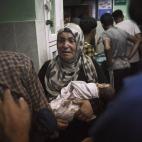 Una mujer sostiene en brazos un bebé herido en el bombardeo de la escuela.