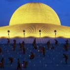 Monjes budistas encienden velas durante el día de Vesak, una celebración anual en recuerdo de Buda, en el templo Wat Dhammakaya en la provincia de Pathum Thani, a las afueras de Bangkok, Tailandia.
