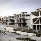 Una mujer pasea bajo las estructuras de cemento de edificios que han quedado a medio construir. Urbanización Convent de les Monges, La Nucia (Alacant).