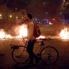 Un ciudadano, con su bicicleta, pasa por una barrera de fuego