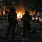 Dos agentes avanzan entre los destrozos en una calle de Barcelona