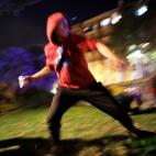 A protestor hurls a rock at police during clashes in Barcelona, Spain, Wednesday, Oct. 16, 2019. Spain's government said Wednesday it would do whatever it takes to stamp out violence in Catalonia, where clashes between regional independence supp...