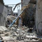 Un hombre camina entre escombros con su hijo