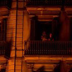 Dos personas observan los disturbios desde un balc&oacute;n en Barcelona.