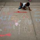 Entre pinturas que homenajean a los muertos y otras que protestan en contra del tiroteo de Dallas, un chico deja su aporte frente a la comisaría de policía de St. Anthony, Minnesota.