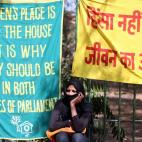 Una mujer india se sienta bajo una pancarta durante una manifestación con motivo del Día Internacional de la Mujer, en Nueva Delhi.